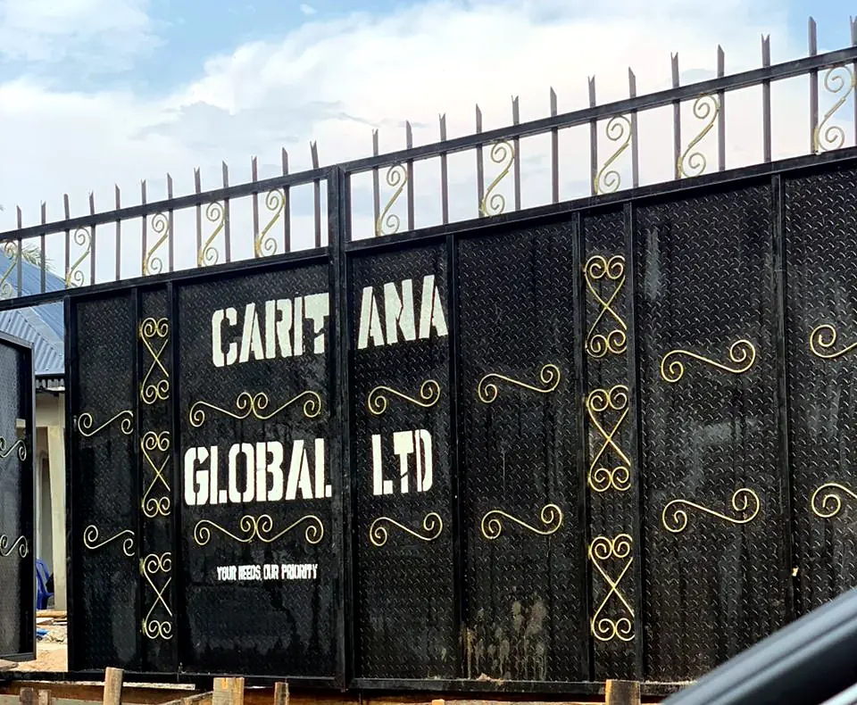 The black and gold gate at the farm entrance, painted with Caritana Global Ltd and the words Your needs, our priority